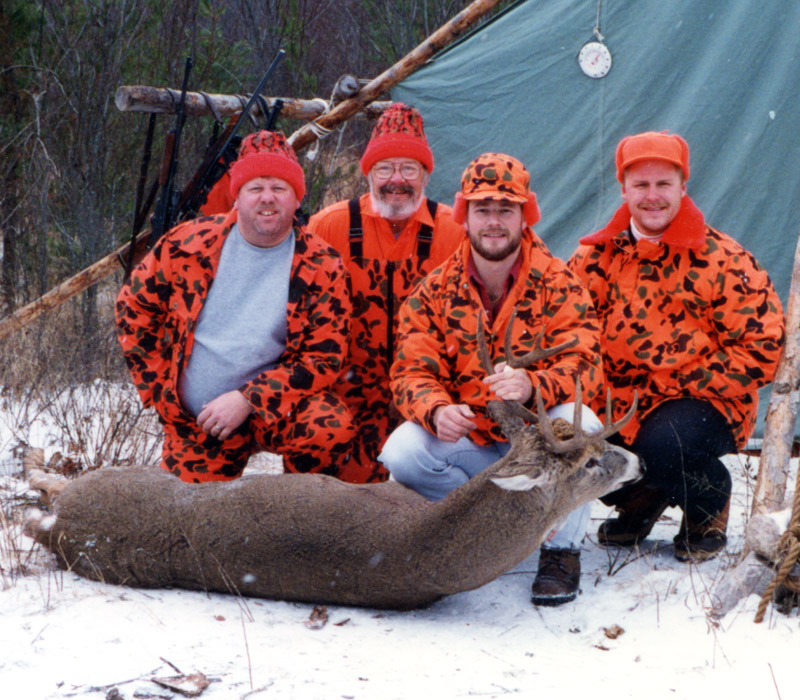 Group photo, 4 men in front of wall tent with Ken's big buck.